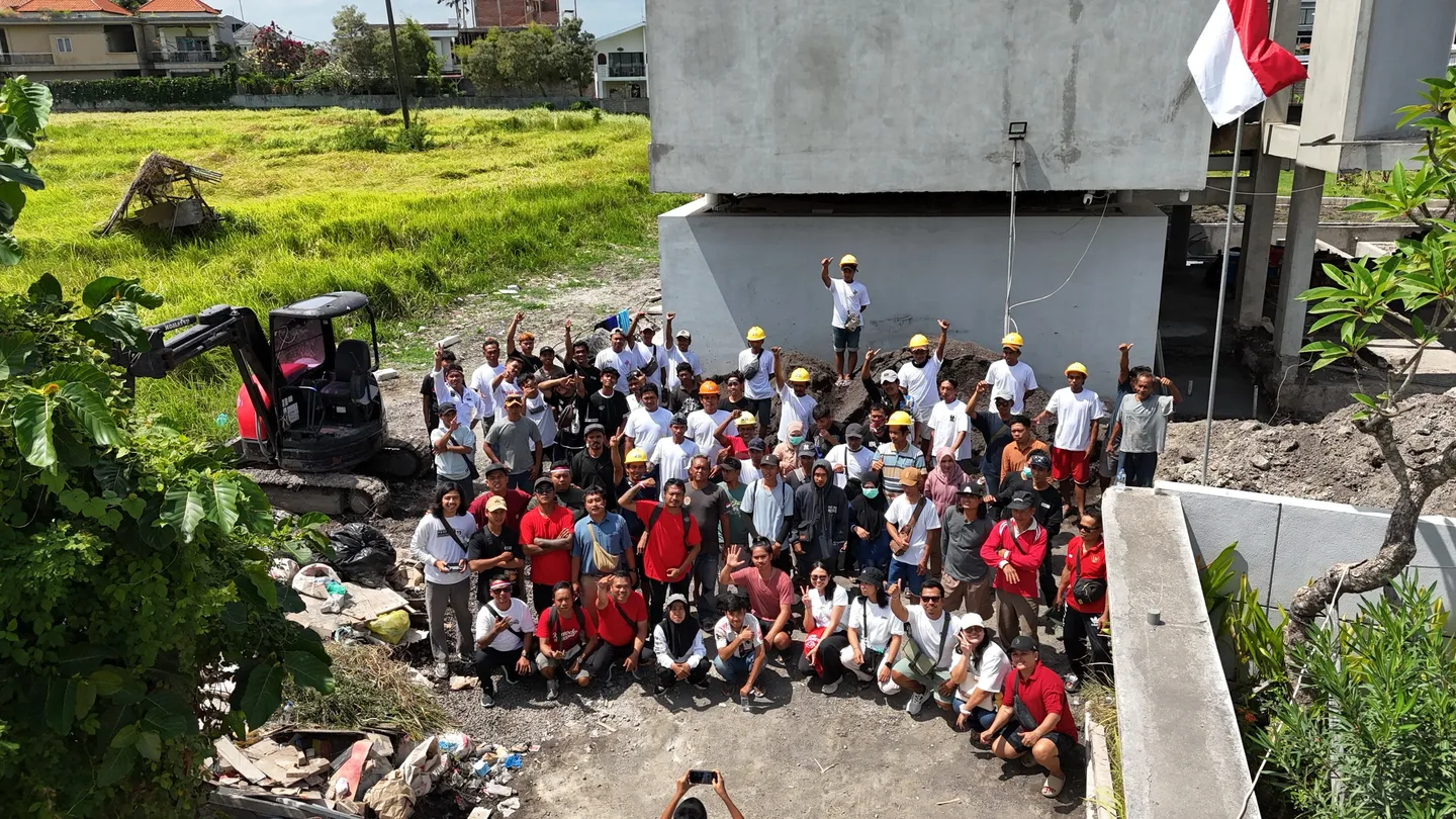 Foto udara tim Perfect 10 Construction berkumpul bersama di lokasi proyek, hitam-putih.