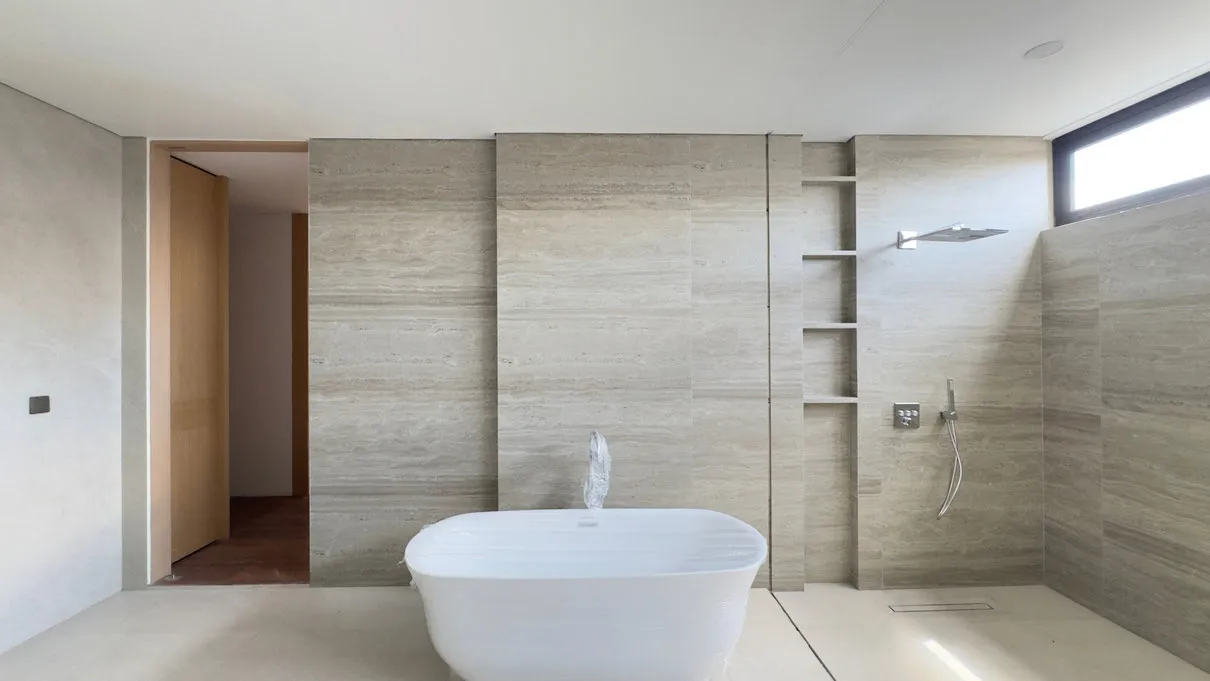 Kamar mandi dengan bathtub lepas dan dinding batu alam.