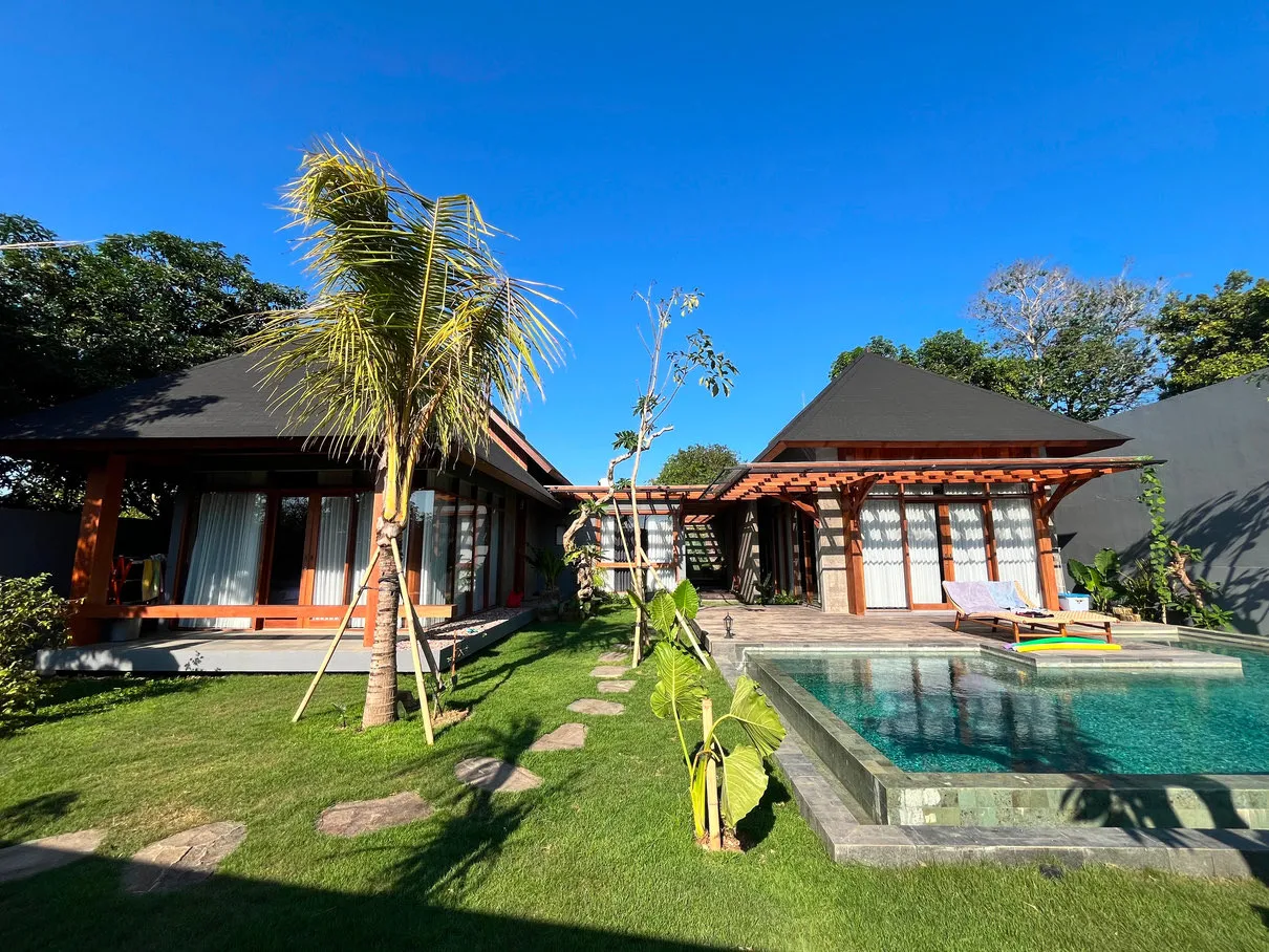 Rumah beratap miring kayu dan hitam dengan kolam renang serta halaman rumput.