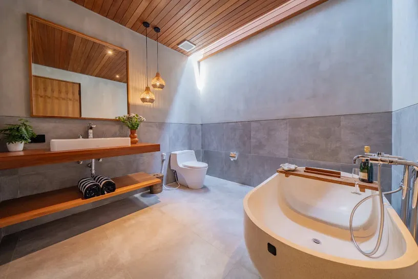 Kamar mandi berlangit-langit kayu dengan bathtub dan cermin.